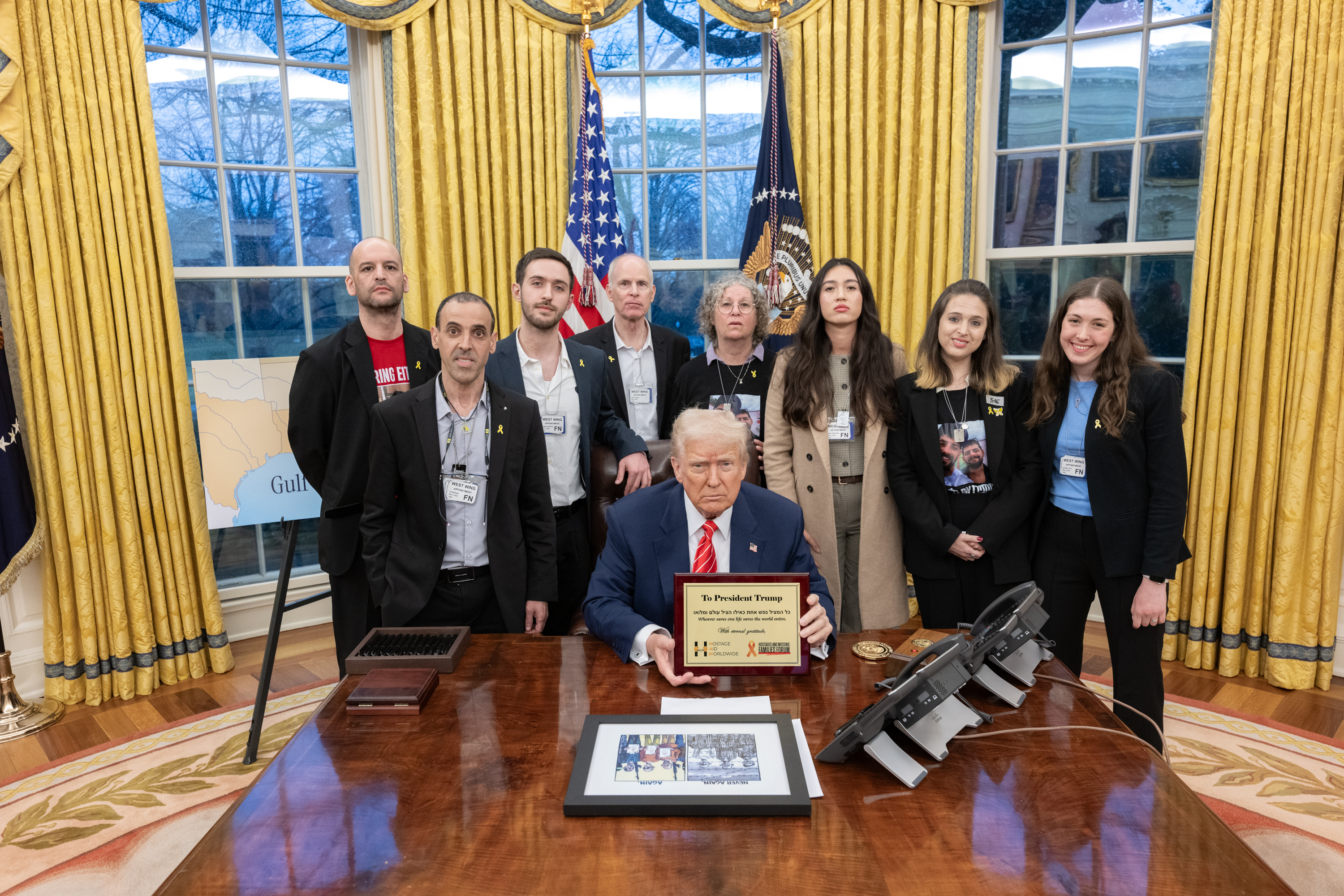 Trump with Eli and other freed hostages. The plaque says, 